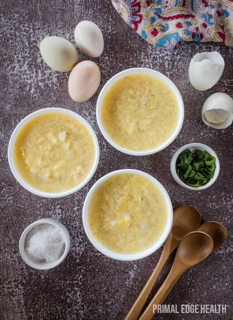 Three bowls of egg drop soup, with wooden spoons placed on the side.