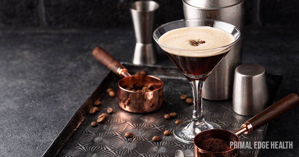 Coffee martini in glass with shaker and bar items in background on silver platter with copper