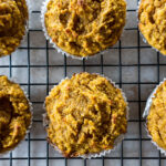 A batch of golden-brown pumpkin muffins on a wire rack.