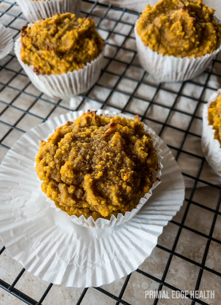 Three keto pumpkin muffins cooling on a wire rack.