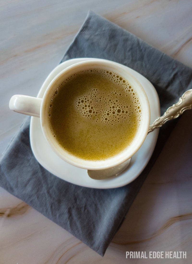 A cup of tea on a saucer with a spoon, resting on a grey napkin.