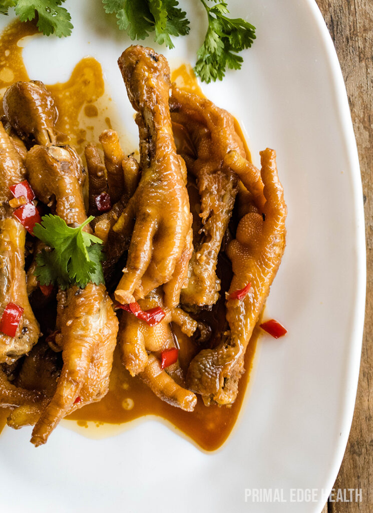 Cooked chicken feet with brown sauce on plate.