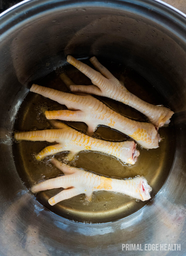 Four chicken feet in pot with oil frying.