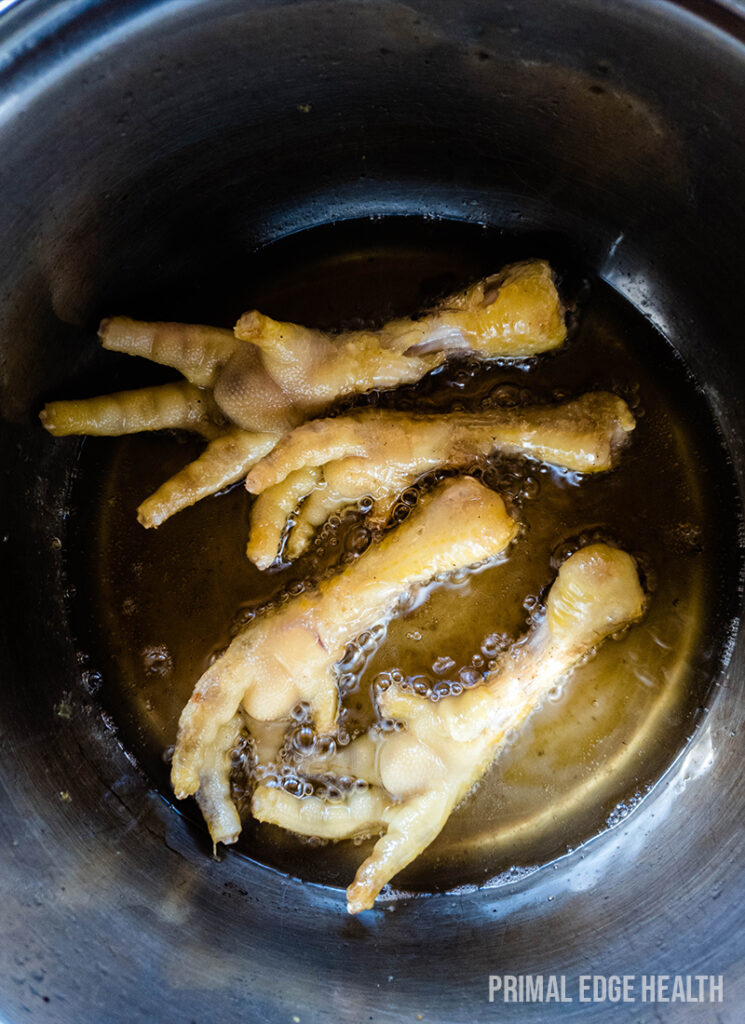 Frying chicken feet in a pot with oil.