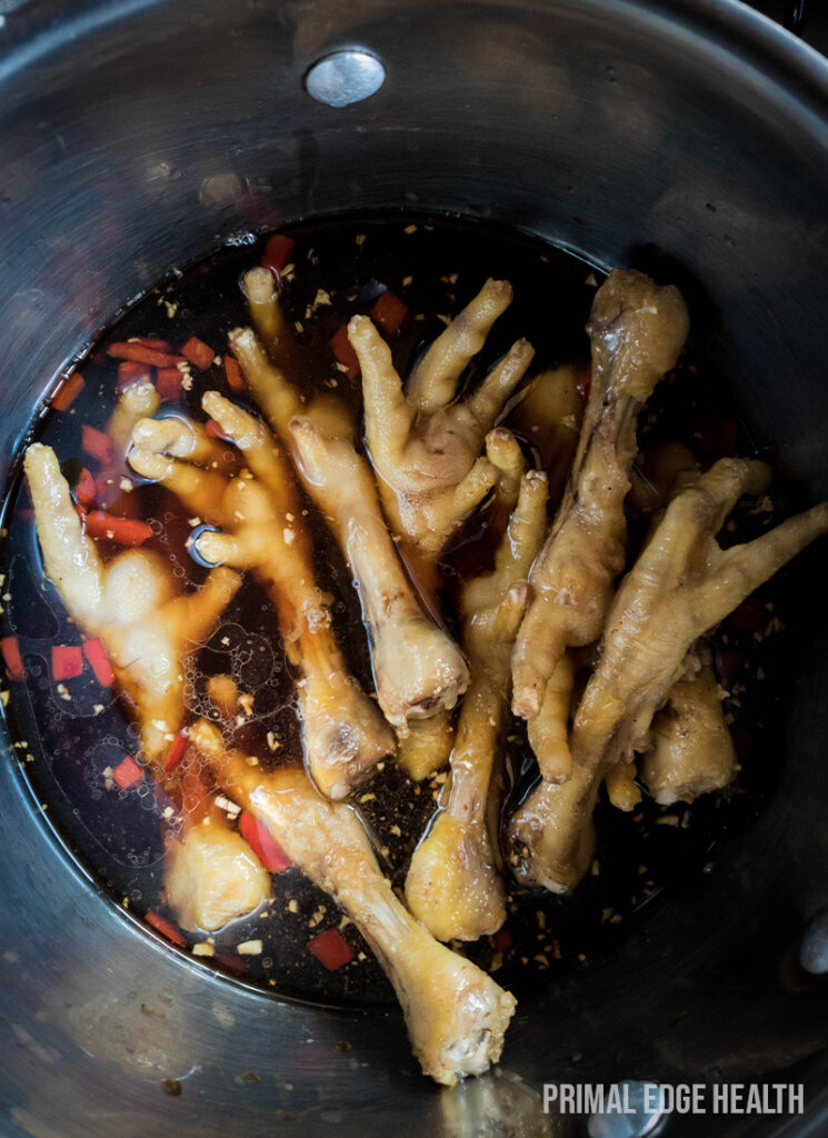 Chicken feet in pot simmering with sauce.