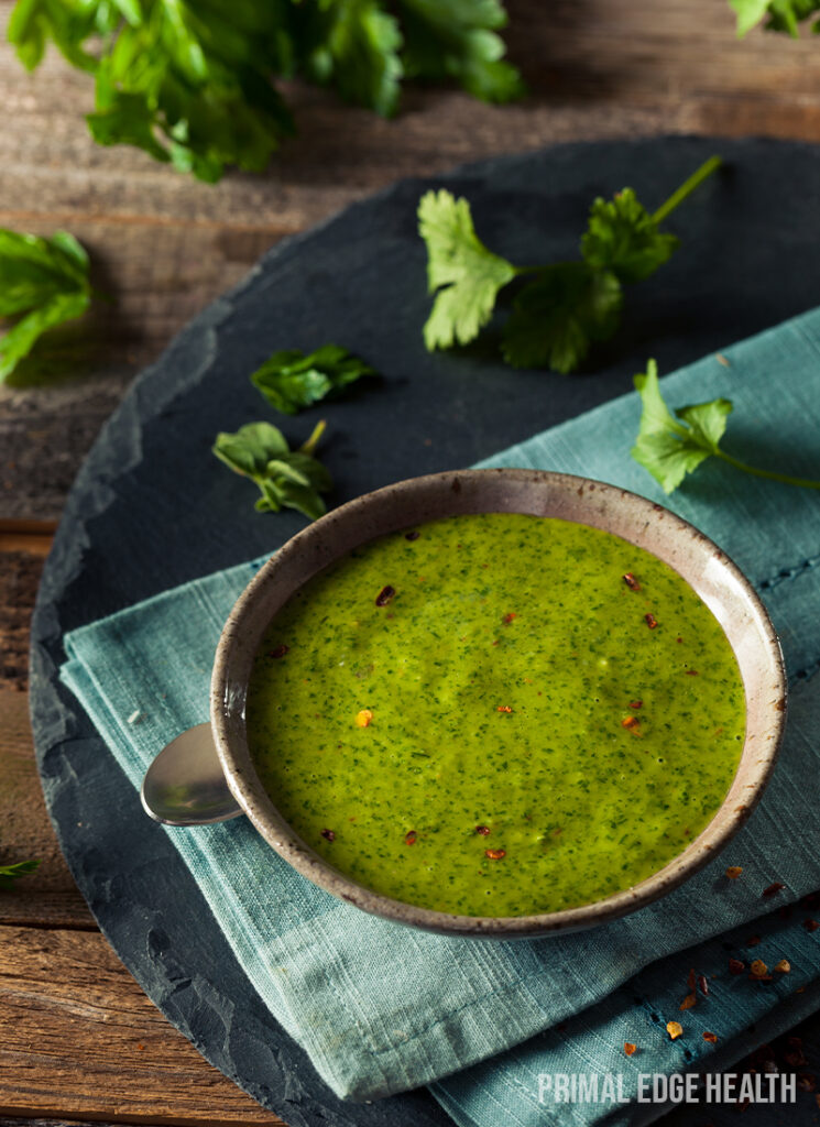 Bowl of vibrant green keto sauce garnished with herbs.