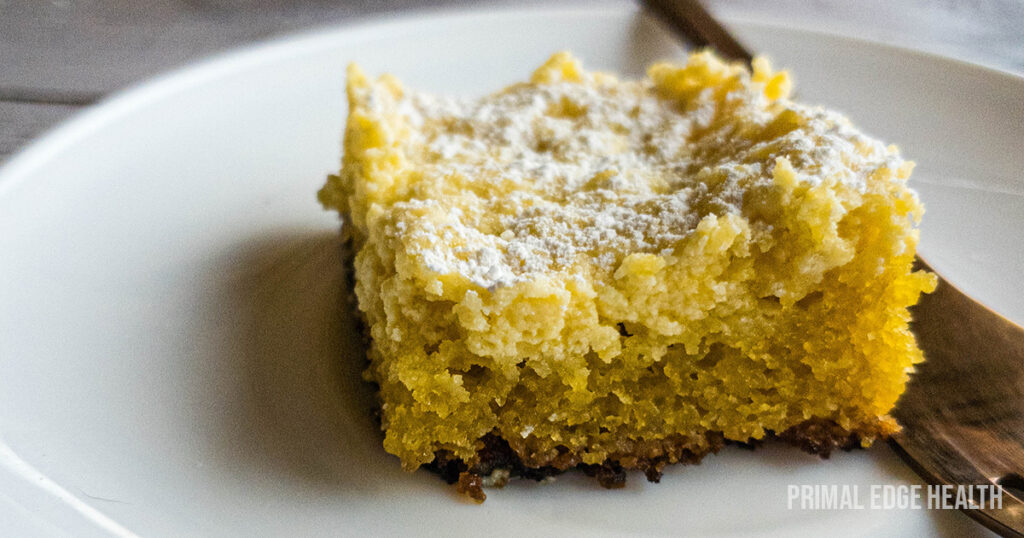 A slice of keto gooey butter cake with powdered on a white plate.