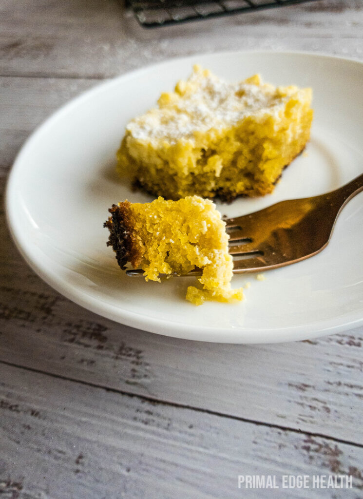 A slice of keto gooey butter cake on a white plate with a fork.