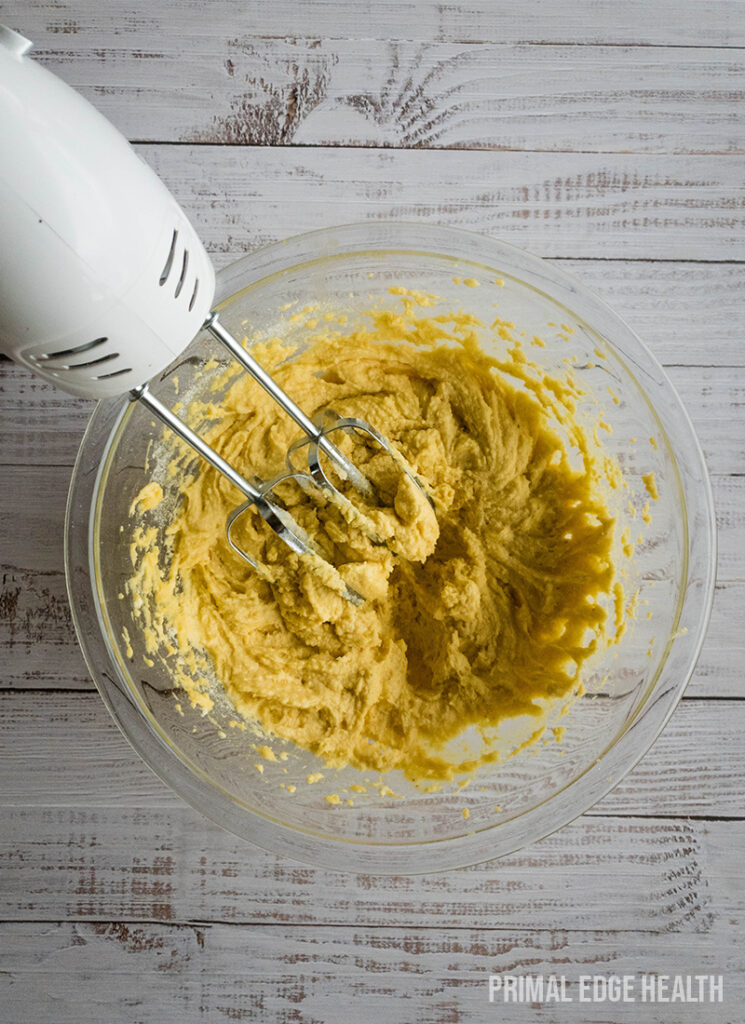 Electric mixer blending ingredients in a glass bowl.