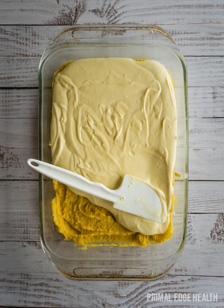 A glass baking dish containing a gooey butter cake, accompanied by a white spatula.