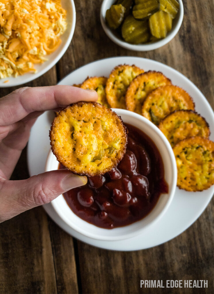 Hand holding a piece of crispy chip above a plate with dipping sauce.