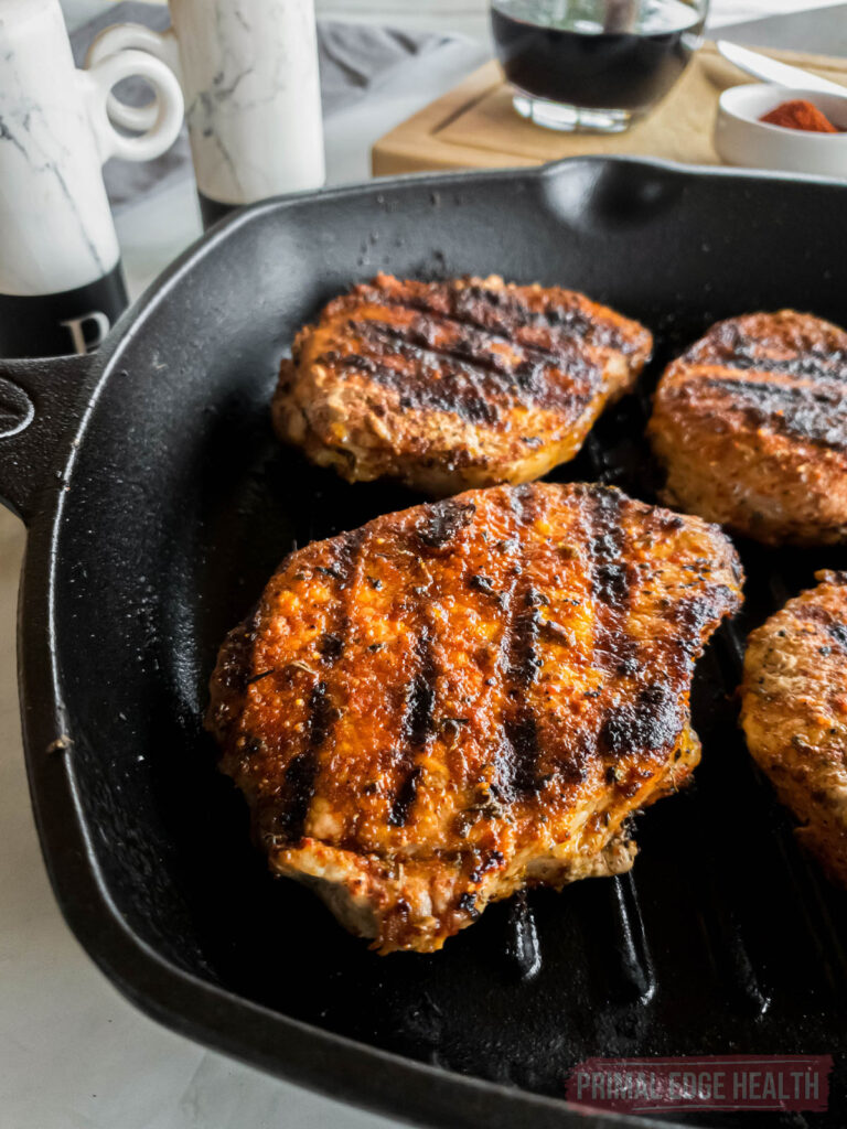 Blackened pork chops with sear marks in a cast iron skillet.