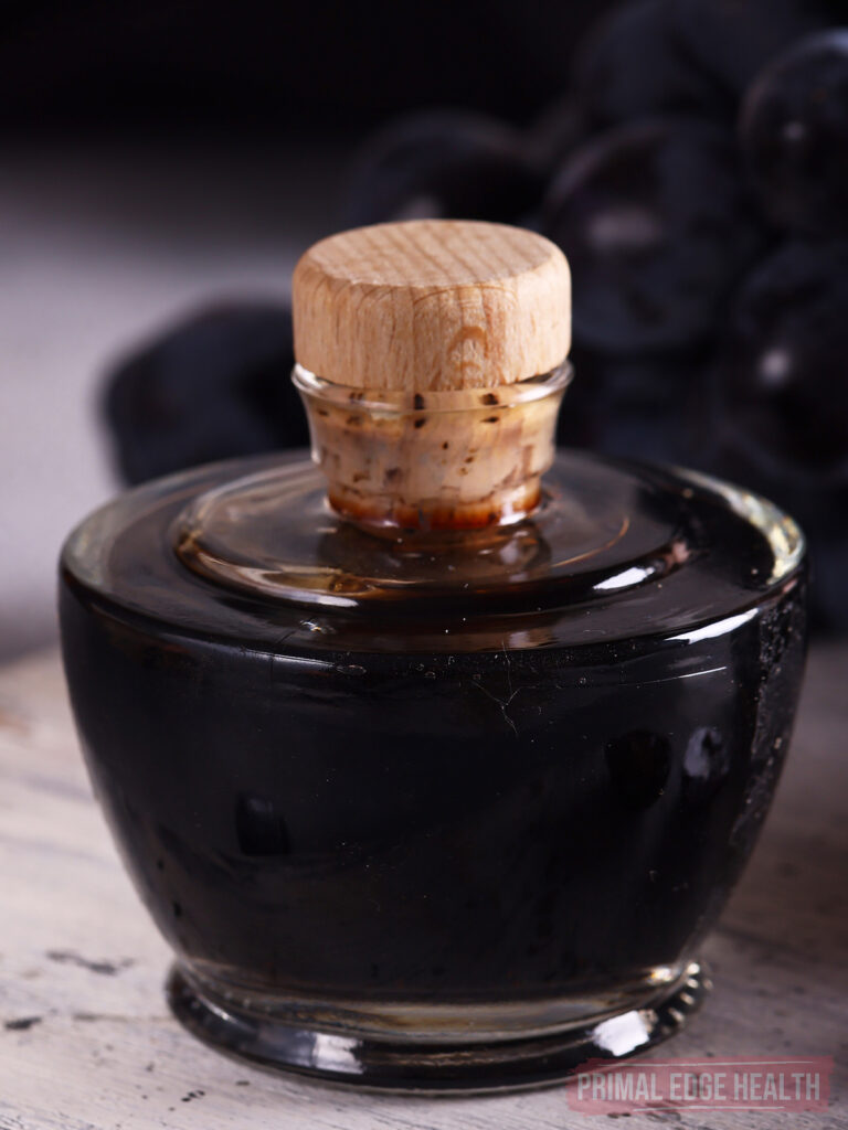 A mini glass bottle with a wooden cork, containing a dark liquid.