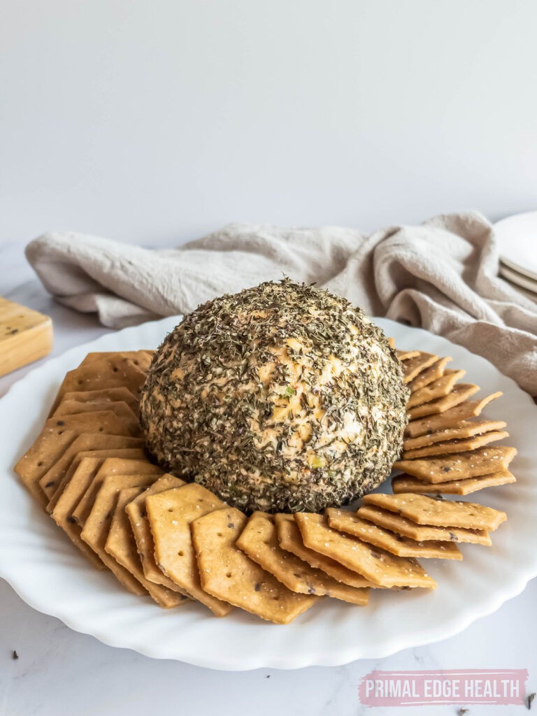 Cheese ball on white serving plate with crackers.
