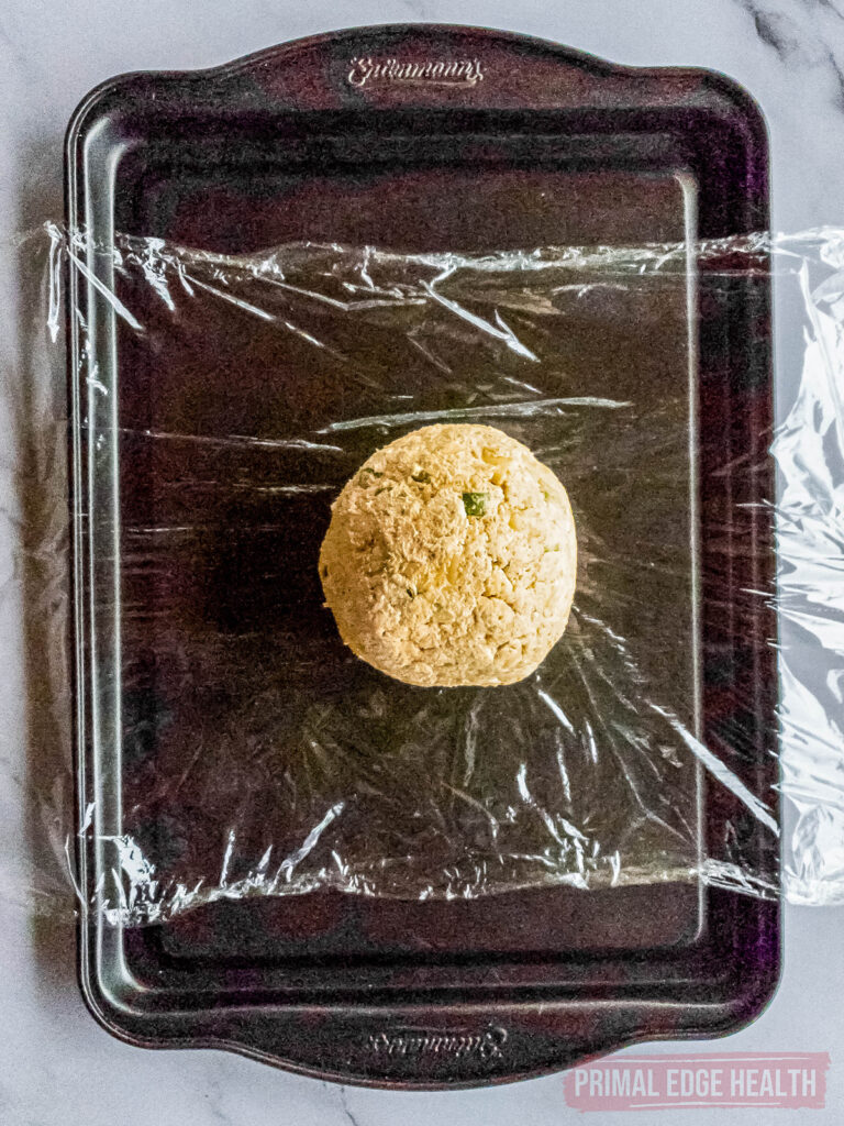 Cheese ball on plastic wrap rolled into a ball.