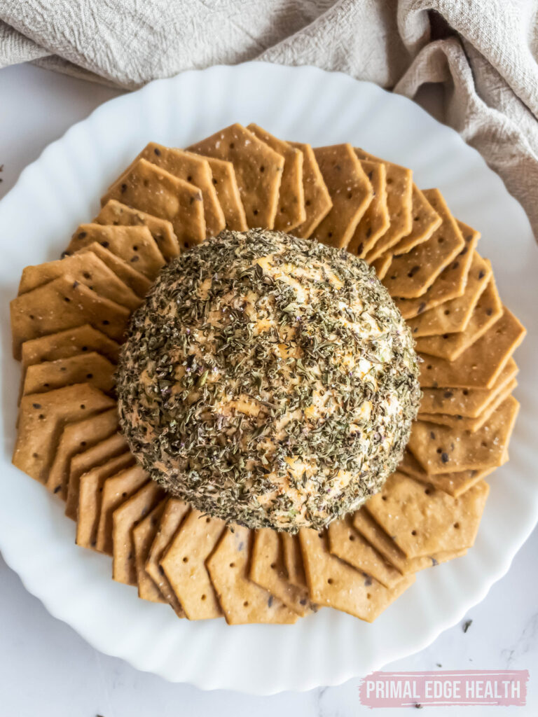 view from above of keto cheese ball on serving plate with crackers around it