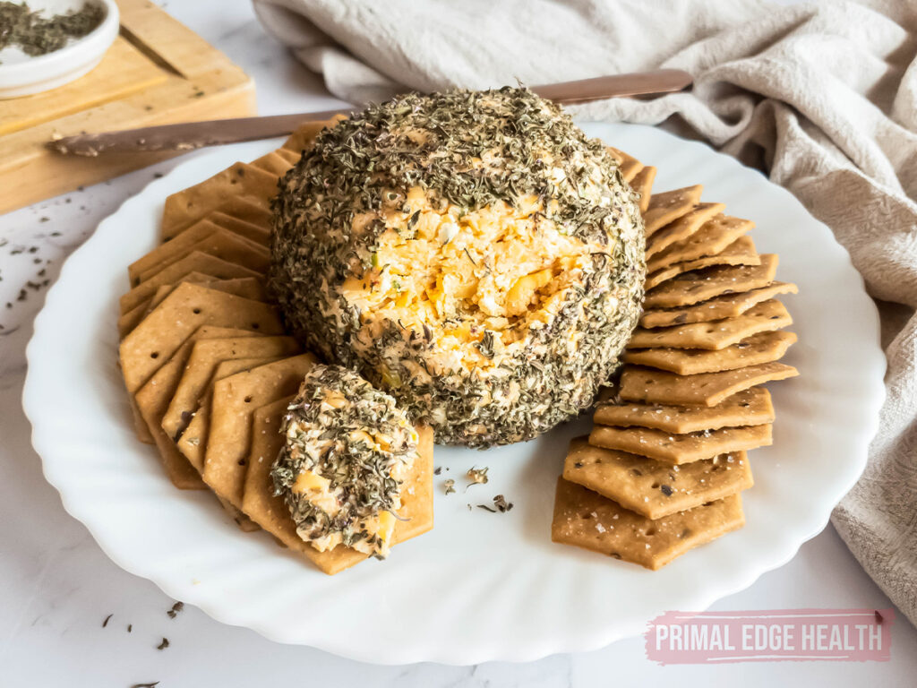 cheese ball rolled in herbs on a plate surrounded with crackers