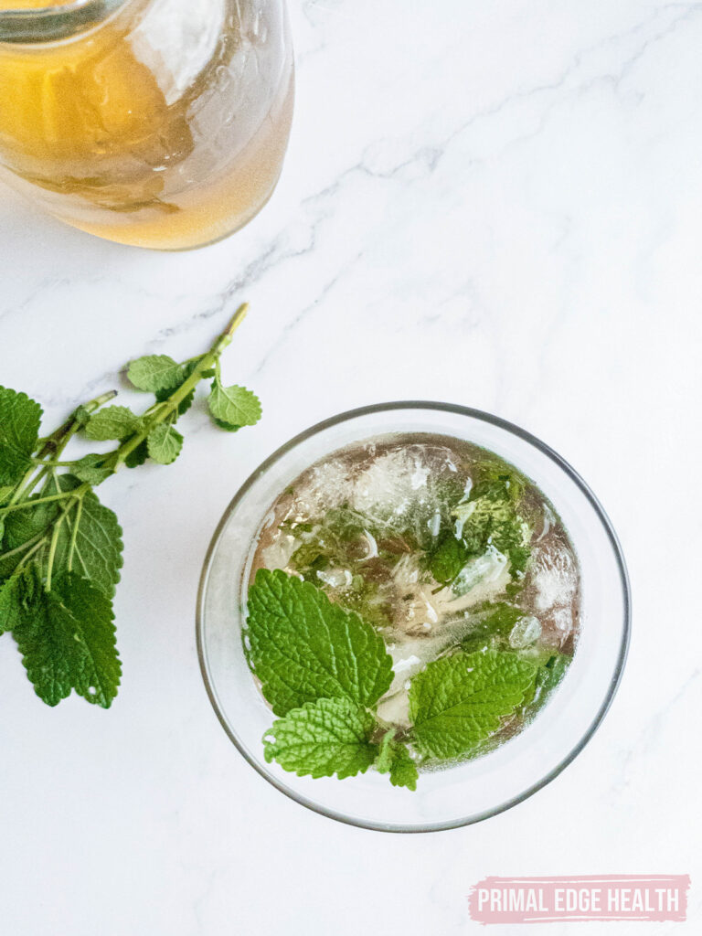 keto-friendly mint julep recipe in glass with ice and muddled mint, bourbon alongside