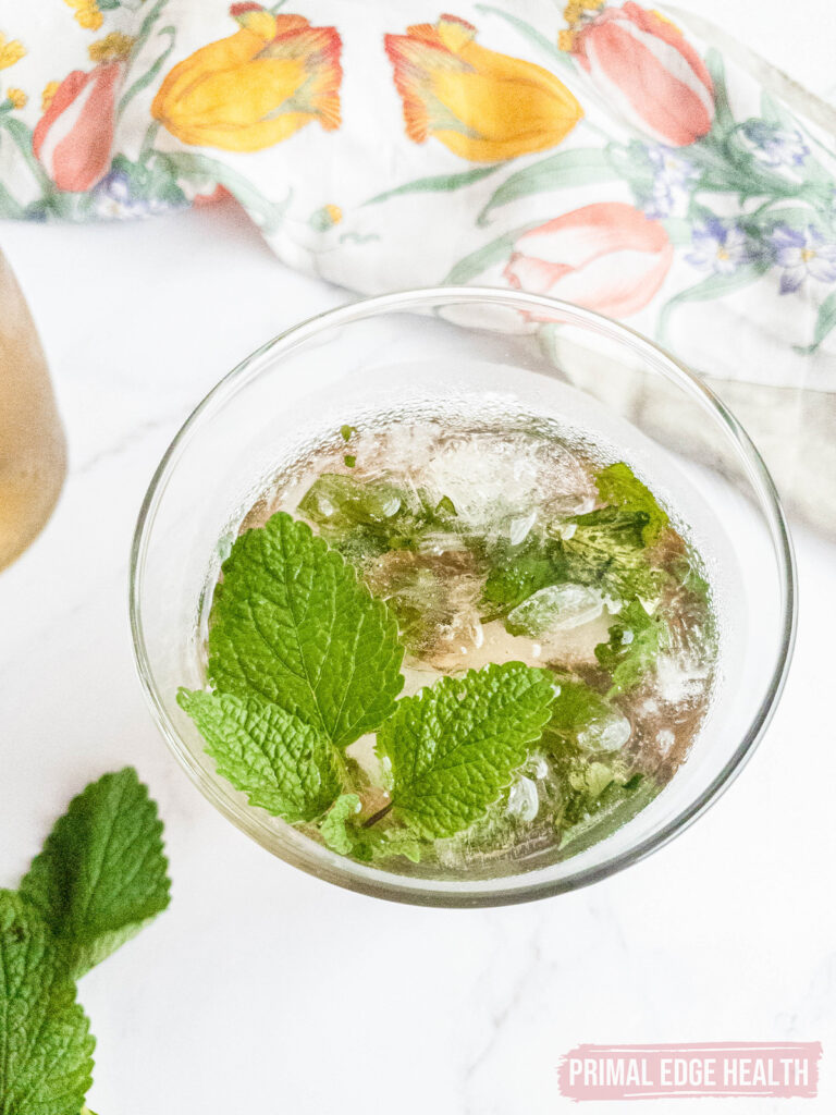 A glass of iced keto mint julep on a white surface.
