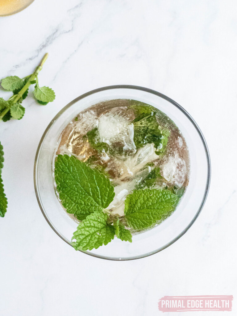 A glass of mint julep on a marble surface.