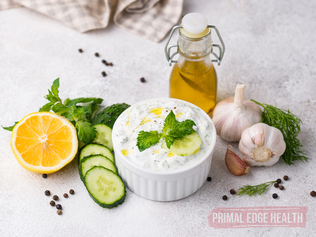 A bowl of keto tzatziki sauce on a white surface.