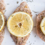 Pork chops seasoned with herbs and lemon slice on top.