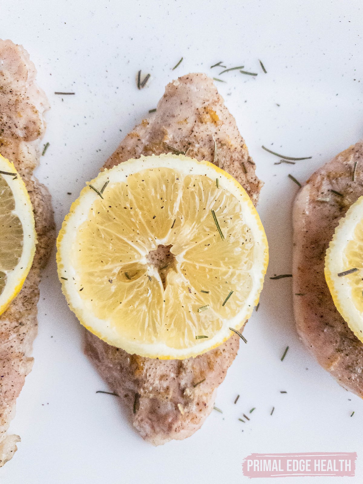 Pork chops seasoned with herbs and lemon slice on top.