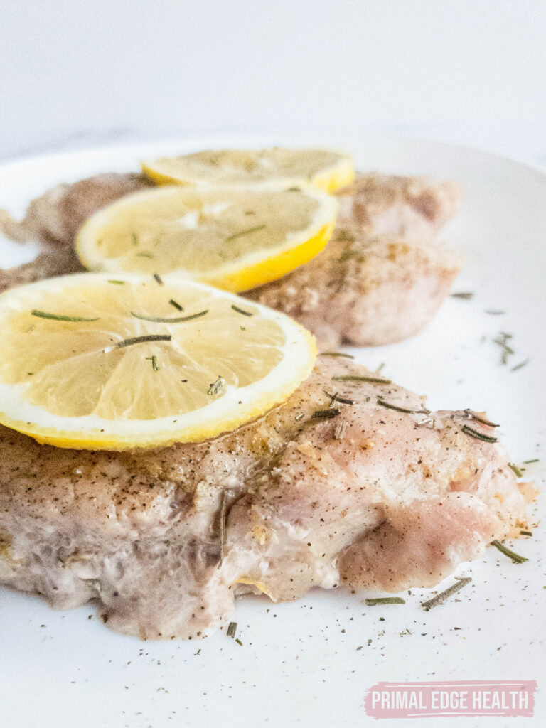 Lemon pepper pork chops on a white plate.