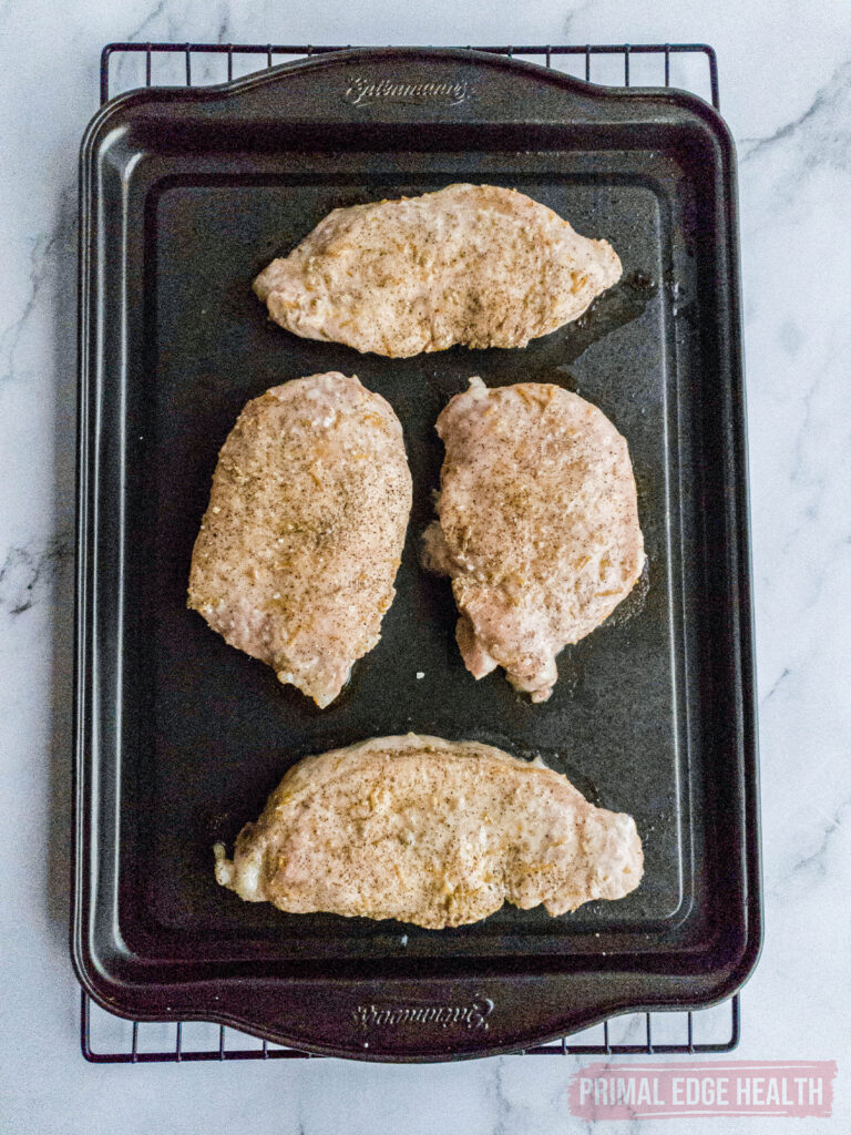 Seasoned pork chops on baking tray ready for the oven.