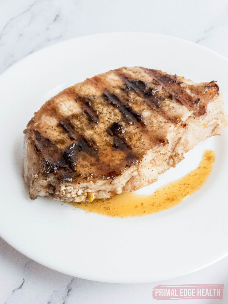 Pork chop drizzled with sauce on a white plate.