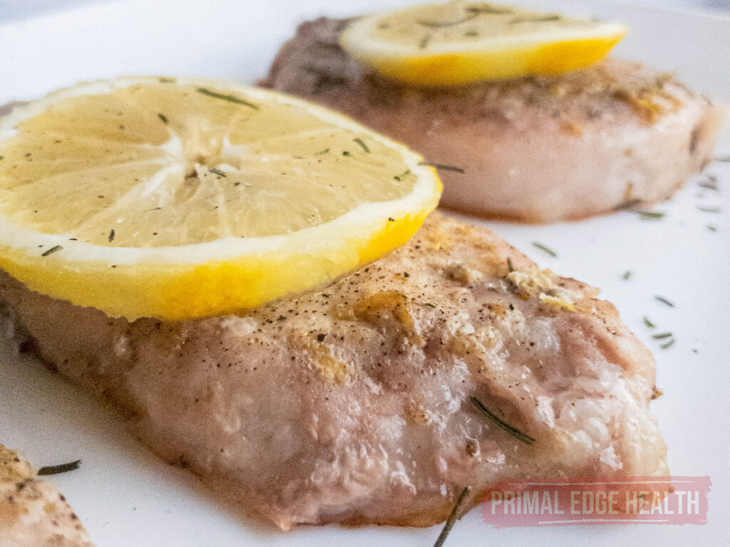 close up view of lemon pepper pork chops with lemon slice on top
