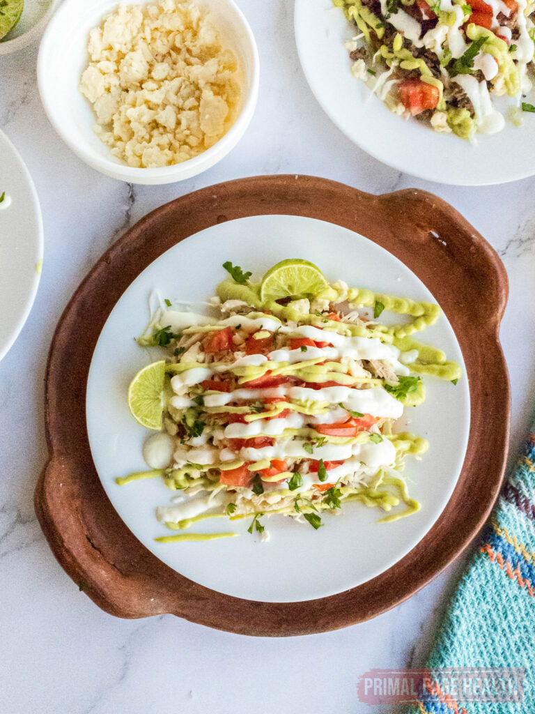 Plate of tostadas with sauce and lime on a wooden serving board.