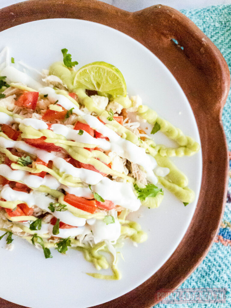 A plate of tostadas topped with lemon, sauce and tomatoes.