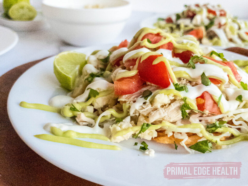 Keto tostada with toppings on a white plate.