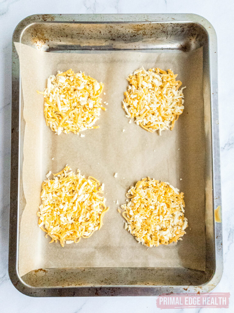 Four cheese mounds on a baking sheet.