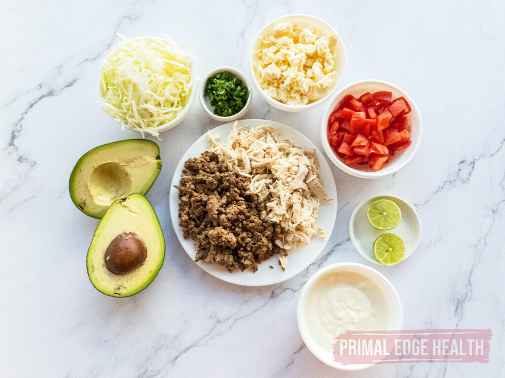 Ingredients for taco salad arranged separately on a marble countertop.