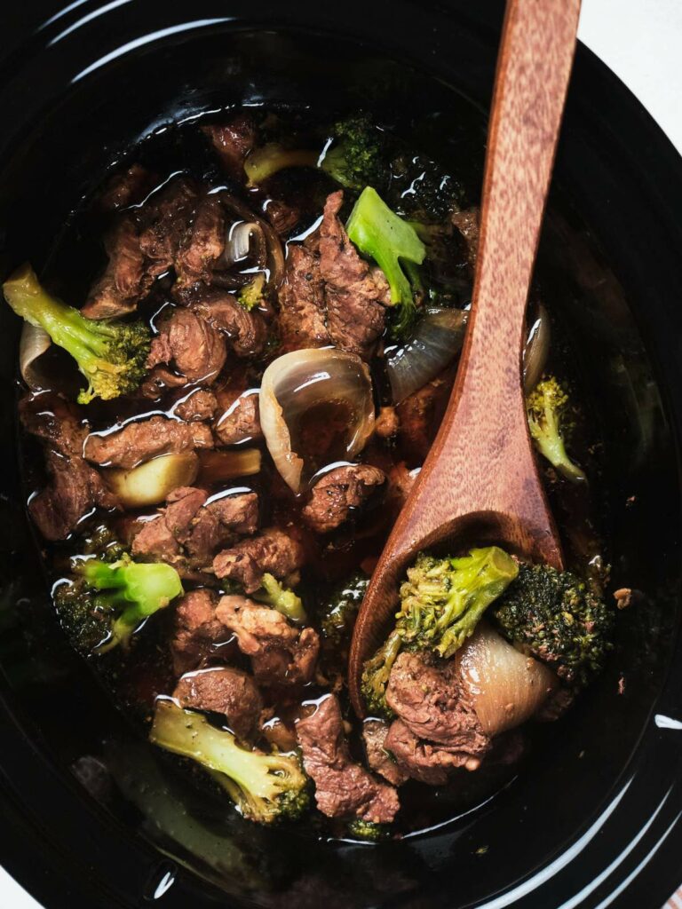 Keto beef and broccoli stir-fry in a black pot with a wooden spoon.