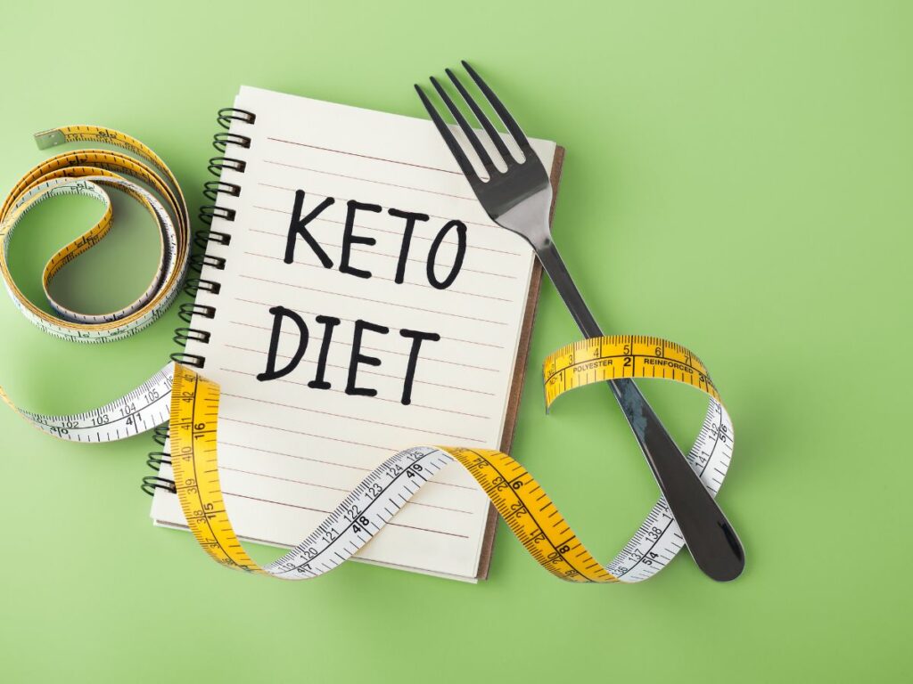 notepad with keto diet, a measuring tape, and a fork