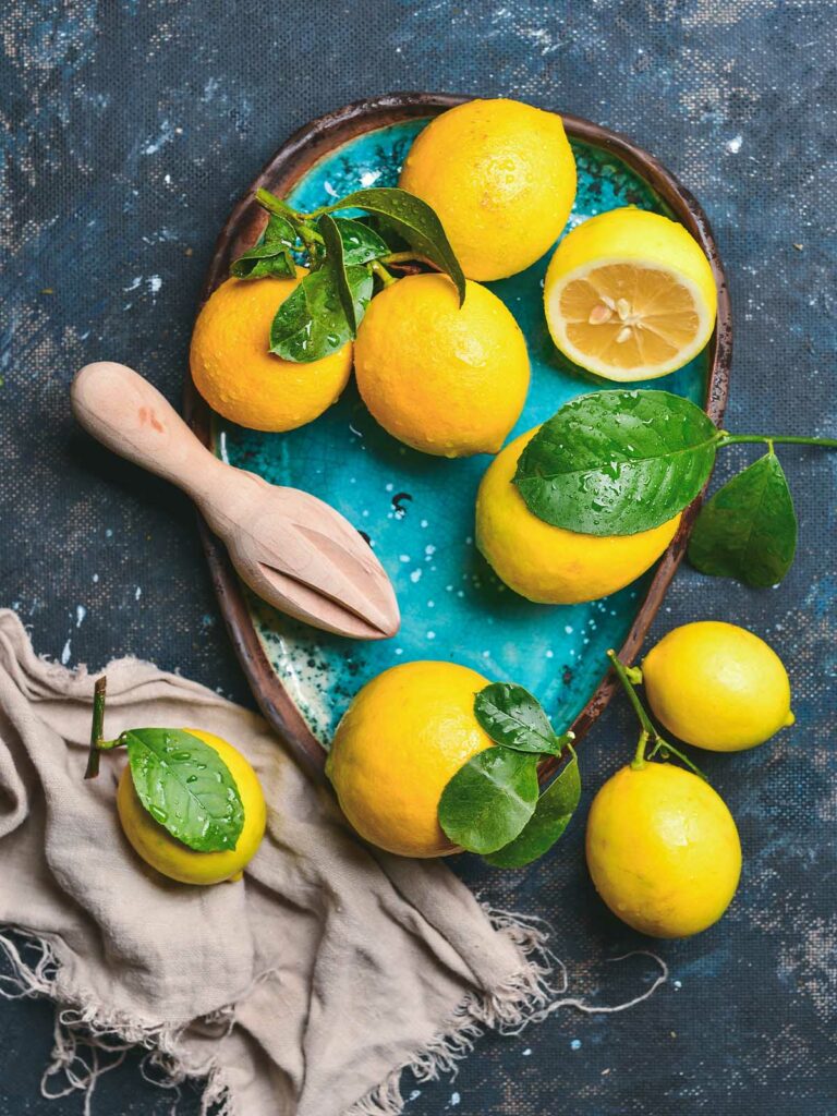 Lemons on tray with cloth in blue background.