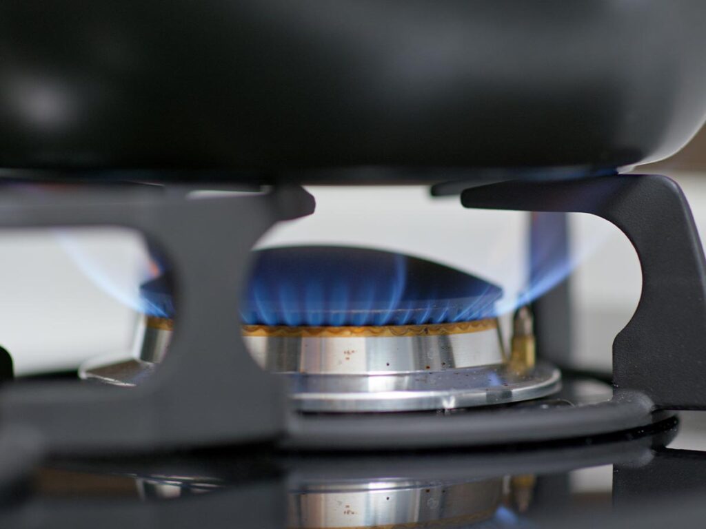 A blue flame on a gas stove under a cast iron skillet, drying it off.