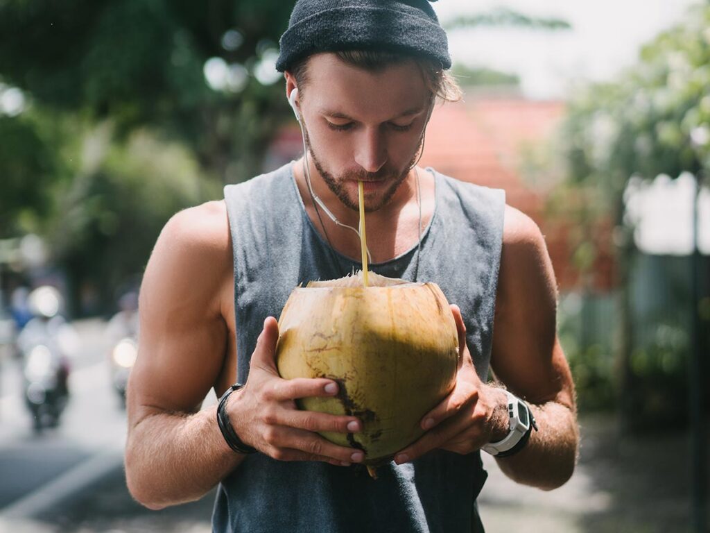 Young man drinking coconut water with a straw.
