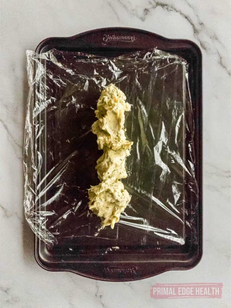 Plastic wrap to roll rosemary garlic butter mixture on baking sheet.