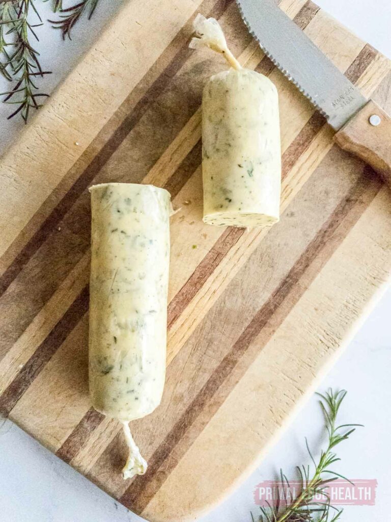 Two halves of rosemary garlic butter roll on wooden board.