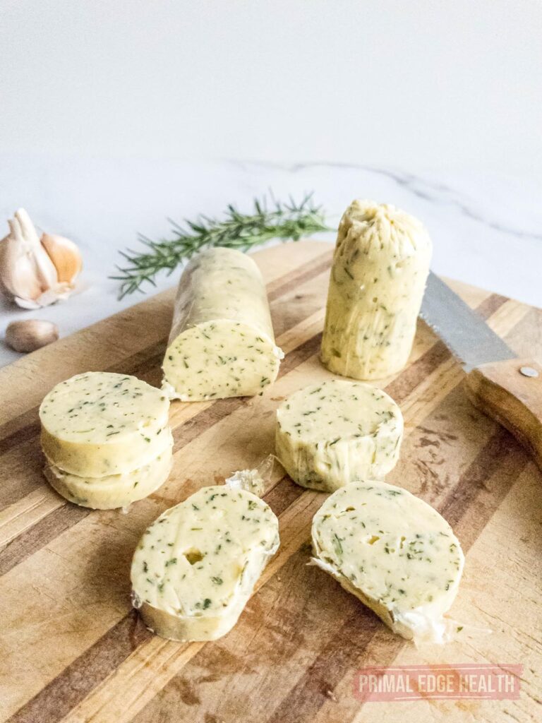 rosemary compound butter in a roll sliced on a wooden cutting board