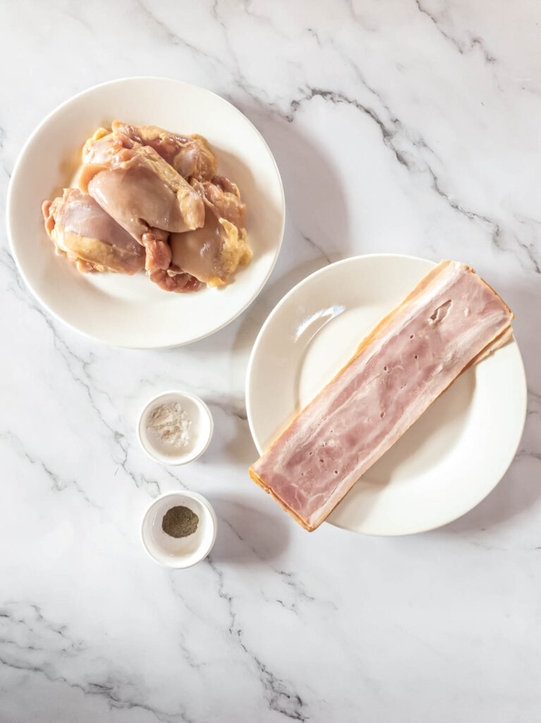 Raw chicken thighs and bacon on a white plate, and salt and pepper.