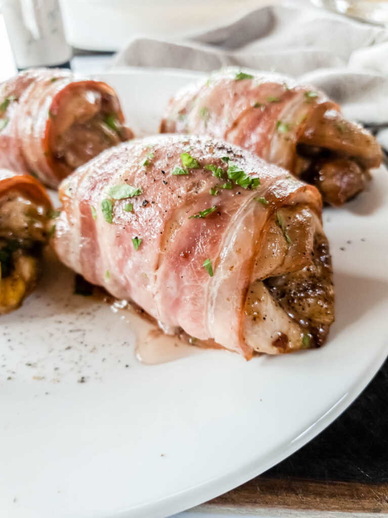 Close up on bacon wrapped chicken thighs with parsley garnish.