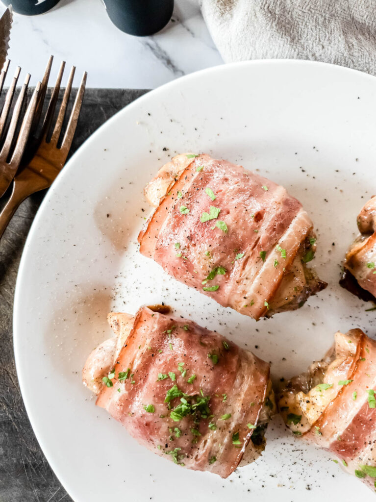 Overhead view of bacon wrapped chicken thighs with copper forks.