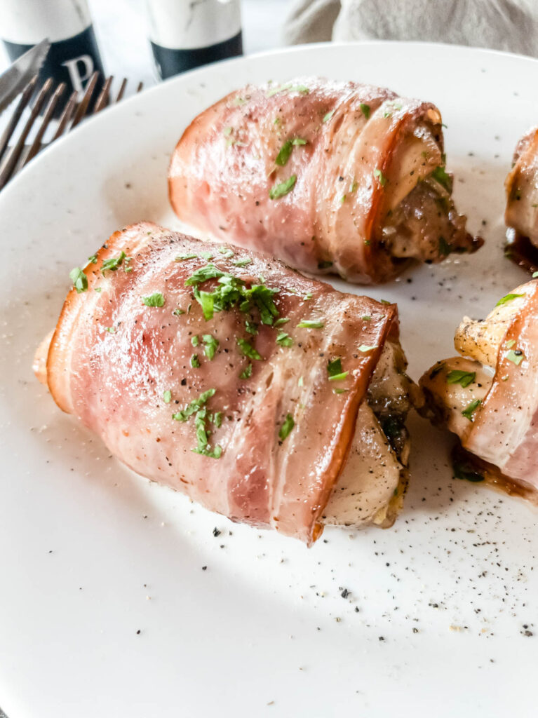 Bacon wrapped chicken thighs on plate, zoomed in.