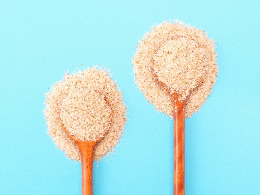 Psyllium husk powder in two wooden spoons.