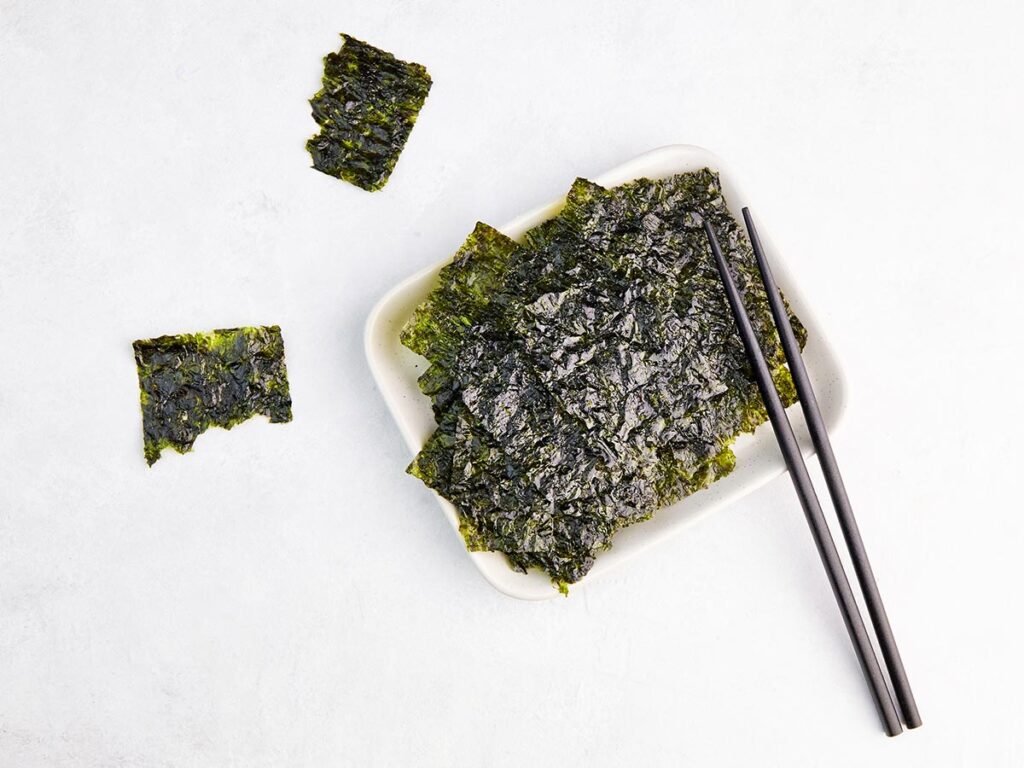 Toasted seaweed snack in bowl with chopsticks.